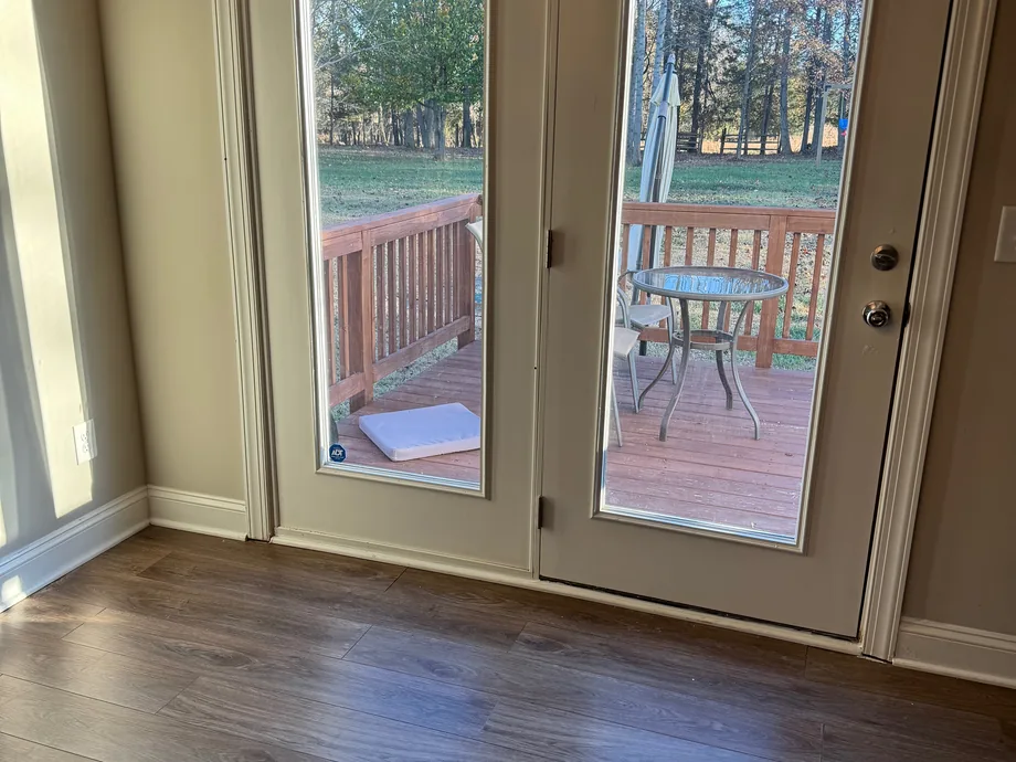 New plank flooring in a room with French doors opening to a deck