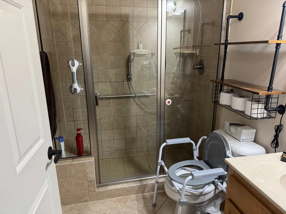 Repaired tile shower with a glass door and shelving